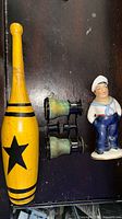 Overall view of wooden club, opera glasses and sailor figurine