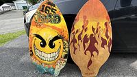 Both sides of the skimboard leaning against car