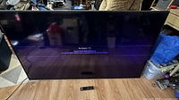 Front view of powered-on 70-inch Vizio TV with remote visible