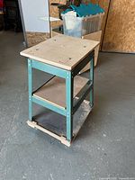 Three-quarter view of steel frame stand with plywood top and shelves