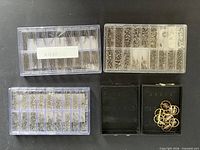 Overview of three clear organiser boxes containing watch screws/pins and two black cases, one holding balance wheels
