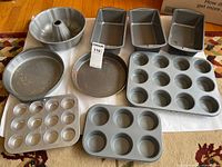 All pans laid out on floor including tube pan, Bundt pan, loaf pans, round cake pan and muffin pans