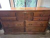 Front view of dresser showing eight exterior drawers, two center doors, brass hardware