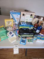 Tabletop view of entire lot showing boxed Aveeno sets, pump bottles, maxi pads, foot file kit, assorted small items