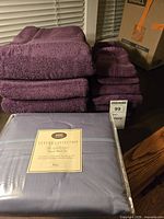 Stacked burgundy towels and sealed blue king sheet set