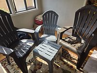 Group view of three plastic Adirondack chairs and square side table