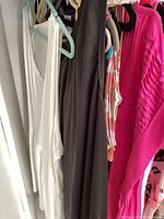 Assorted sleeveless tops on hangers: white, charcoal, print, bright pink