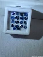 Front view of 18 round blue sapphires in gem box