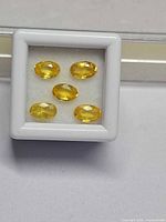 Five oval yellow sapphires in white gem box frontal view