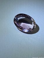 Oblique view of faceted oval amethyst on neutral background