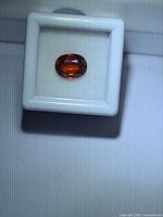 Top view of oval orange gemstone in display box