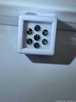 Six green sapphires in display box, overall view