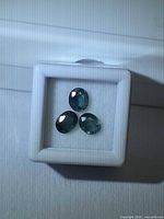 Three oval blue-green sapphires in white gem box