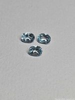 Three oval sky blue topaz gemstones on neutral background