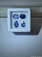 Four blue sapphires in display box, two ovals top, two pears bottom