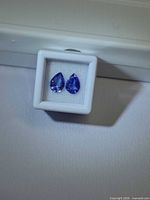front view of two loose pear-cut tanzanites in display case