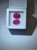 Two oval rubies in white display box, top view
