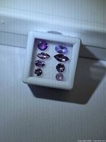 Parcel of eight faceted pink-lavender tanzanites in display case