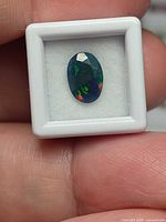 Front view of the faceted oval opal in display box showing multicolour play