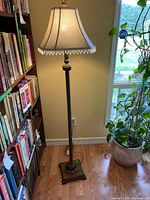 Full view of floor lamp beside bookshelf and plant