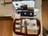 Overview of lot showing Swissmint cases, Canadian Armistice folder and bagged circulation coins in bin