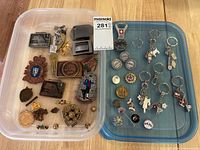 Overall view of two containers with keychains, belt buckles, pins and bottle opener