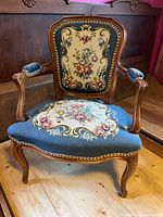 Front view of French-style armchair showing frame, upholstery and nailhead trim