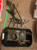 basket holding ornate cast iron pieces, wrought iron chain with hooks and wall rack