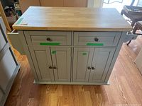 Front view of gray kitchen island cart showing two drawers, four cabinet doors, wood top
