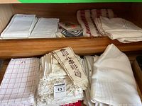 Stacks of assorted folded linens on two shelf levels