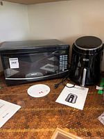 RCA microwave and Ultima Cosa air fryer side by side on countertop with manual visible