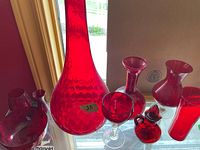 Group shot of red glassware including vases, goblet, pitcher