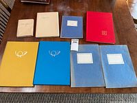 Eight closed albums of varying colours on table