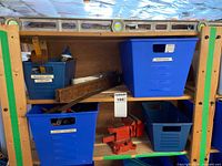 Shelf with bins, wooden and metal tools, red vises visible