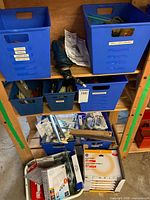 Overview of shelving with blue bins holding drill, manual, driver kits, bulbs, and hardware