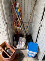 Overall lot inside storage cabinet showing Toro Power Shovel, cords, tools, sand, bucket, pots