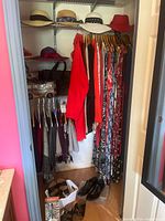 Closet view showing hanging garments, hats on shelf, shoes on floor