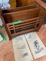 Wooden magazine rack with two prints on floor