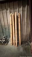 four of the reclaimed 2x4 studs leaning against metal wall