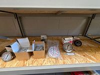 Row of seven 2.5 in pressure gauges, some boxed, some bagged, on shelf