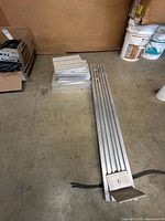 Two long aluminum rails and stack of shorter rails on floor