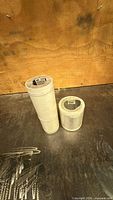 Two cylindrical packaged aluminum flashing coils on work surface