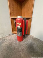 Full view of red Ansul fire extinguisher standing upright with hose attached