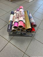 Stack of twelve assorted HTV rolls in clear acrylic bin showing varied colours and finishes