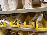 Multiple yellow bins holding sealed envelopes and boxed pump repair kits