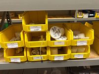 Yellow bins holding multiple white nylon adapters, plugs and connectors