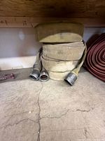 Entire coiled canvas fire hose with both threaded ends visible