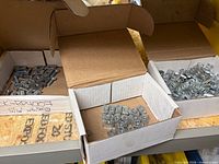 Three boxes containing channel nuts and spring channel nuts on shelf