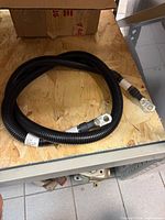Coiled black corrugated-loom battery cable with ring terminals