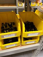 Two yellow bins filled with black rubber-lined steel pipe clamps